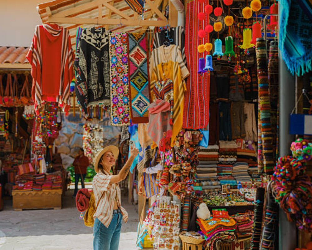 Woman photographing with smartphone on Pisac Market during experiential trip in Sacred Valley, Peru