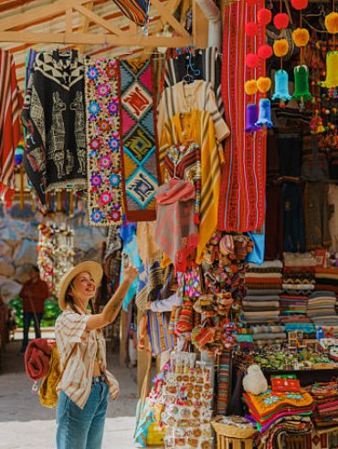 Woman photographing with smartphone on Pisac Market during experiential trip in Sacred Valley, Peru